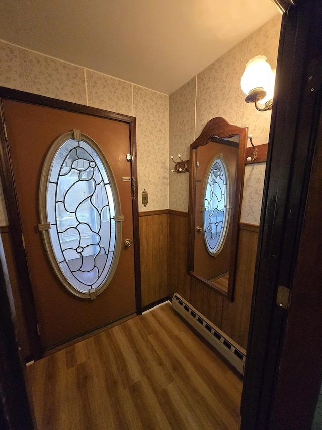 doorway featuring hardwood / wood-style floors, baseboard heating, and wooden walls