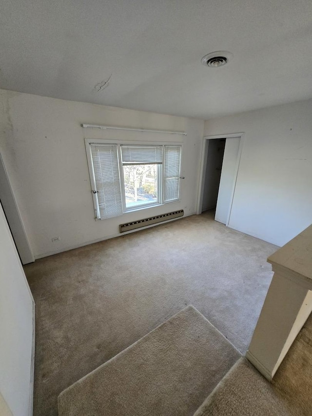 empty room featuring a textured ceiling, carpet floors, and a baseboard radiator