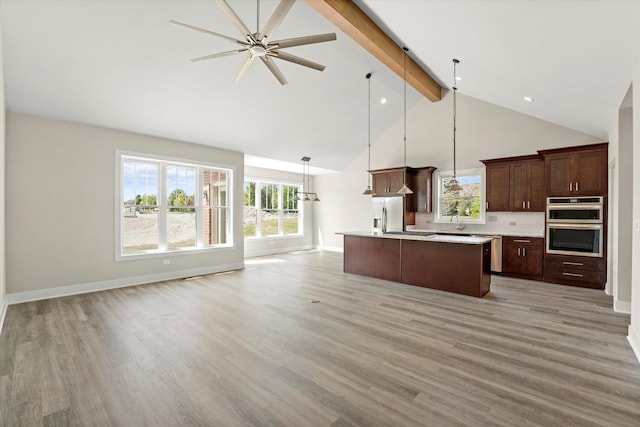 kitchen with pendant lighting, beamed ceiling, light hardwood / wood-style floors, and a kitchen island