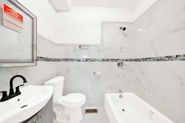 full bathroom with tile walls, vanity, toilet, and tiled shower / bath combo