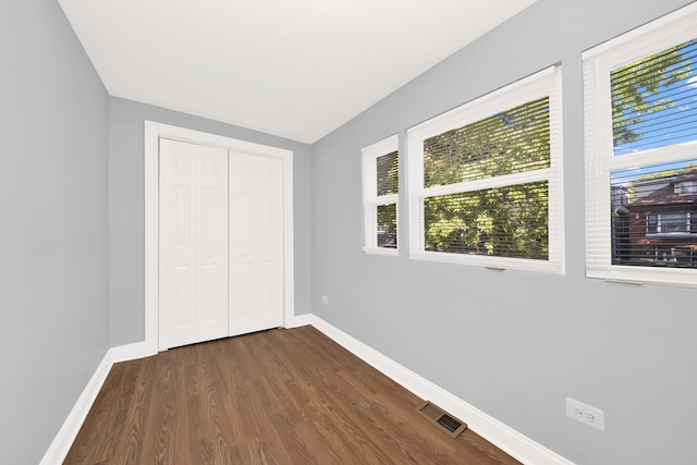 unfurnished bedroom featuring a closet and dark hardwood / wood-style flooring