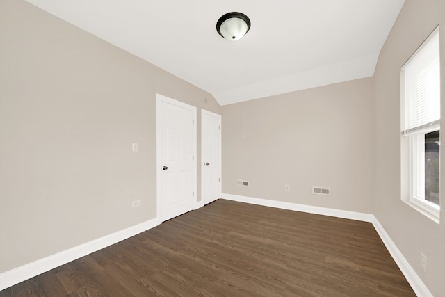 spare room with lofted ceiling and dark wood-type flooring