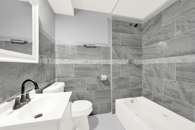 full bathroom with tile walls, vanity, toilet, and tiled shower / bath