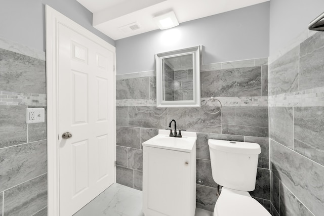 bathroom with tile walls, vanity, and toilet