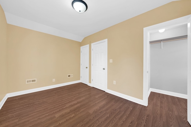 unfurnished bedroom featuring lofted ceiling and dark hardwood / wood-style flooring