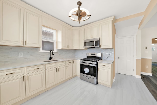 kitchen featuring appliances with stainless steel finishes, cream cabinetry, tasteful backsplash, light hardwood / wood-style flooring, and sink