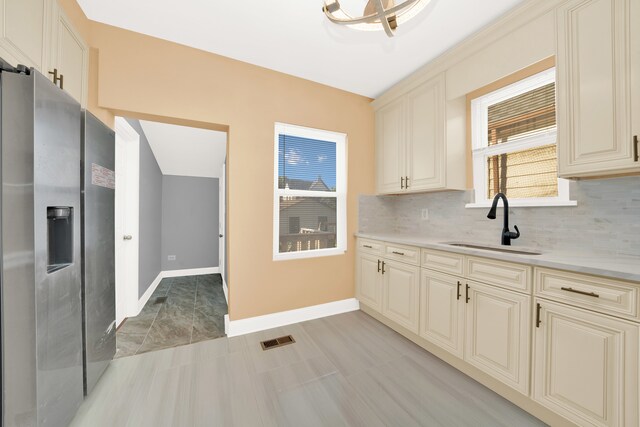 kitchen featuring backsplash, sink, stainless steel fridge with ice dispenser, and cream cabinetry