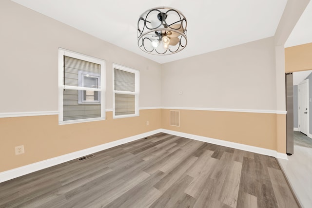 empty room with wood-type flooring and a chandelier