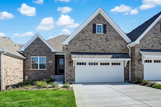 view of front facade featuring brick siding, driveway, and a shingled roof