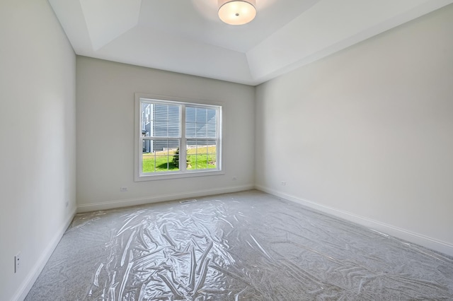 carpeted spare room featuring baseboards and a raised ceiling