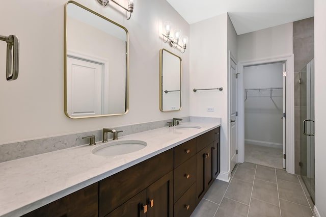 full bathroom featuring a shower stall, double vanity, a sink, and a walk in closet