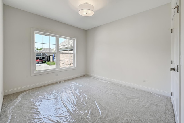 spare room featuring light carpet, baseboards, and visible vents
