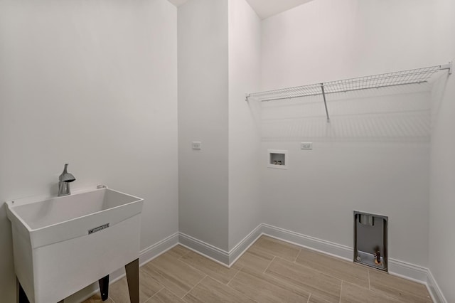 laundry area featuring baseboards, washer hookup, laundry area, wood tiled floor, and a sink