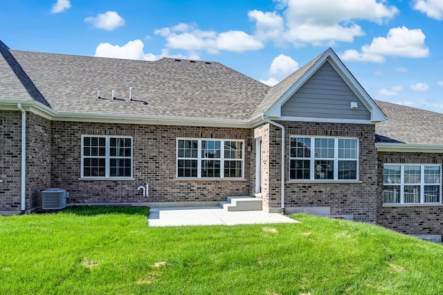 back of house with central AC unit, a lawn, a patio, brick siding, and roof with shingles