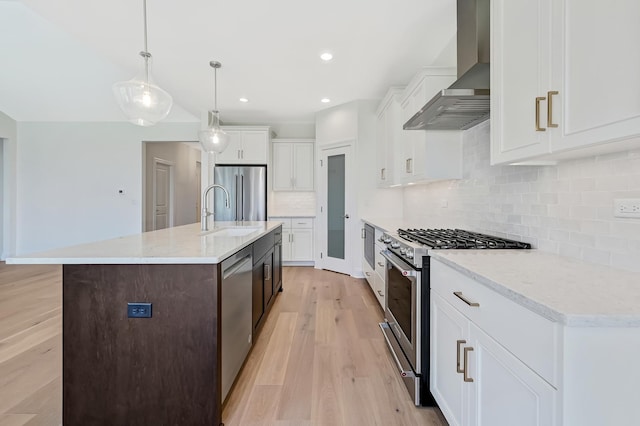 kitchen featuring light wood-type flooring, a sink, wall chimney exhaust hood, and stainless steel appliances