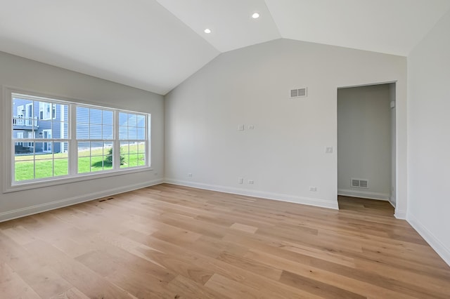 spare room featuring light wood-style floors, baseboards, lofted ceiling, and visible vents