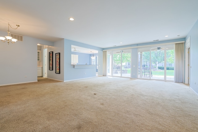 unfurnished living room featuring light carpet and ceiling fan with notable chandelier