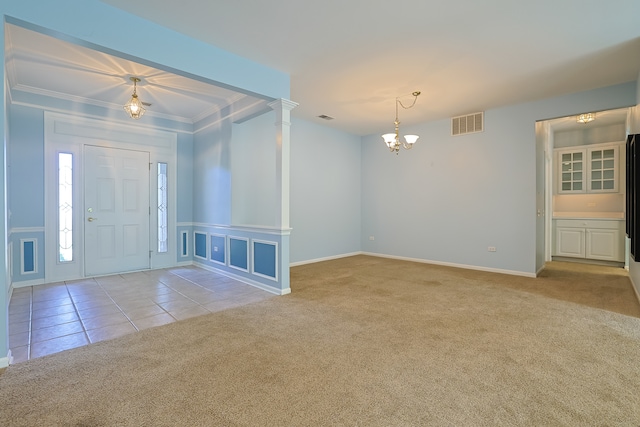 carpeted foyer with crown molding and an inviting chandelier