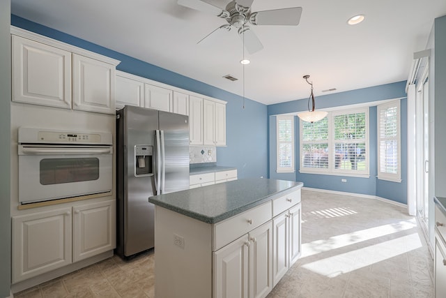 kitchen featuring a center island, stainless steel fridge with ice dispenser, white cabinetry, oven, and ceiling fan