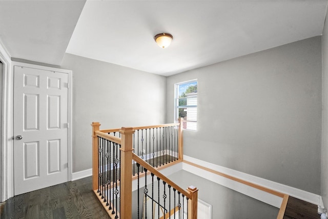 hallway with an upstairs landing, dark wood-style flooring, and baseboards