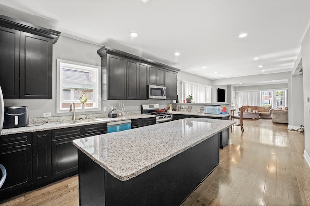 kitchen featuring light stone counters, a kitchen island, stainless steel appliances, light hardwood / wood-style flooring, and sink