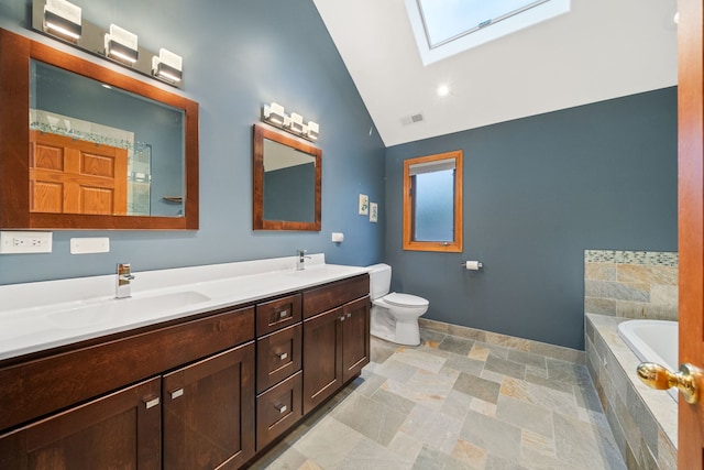 bathroom featuring vaulted ceiling with skylight, tiled bath, vanity, and toilet