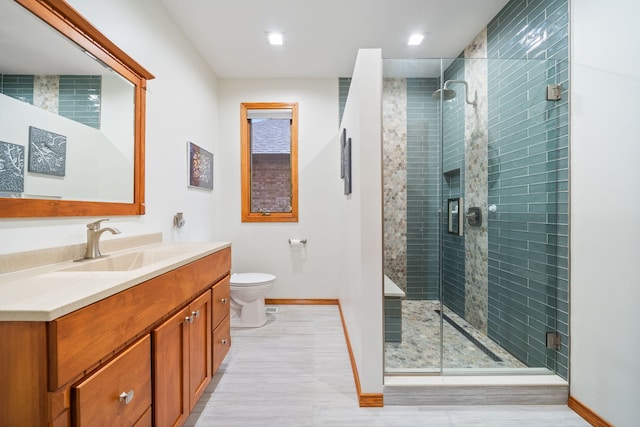 bathroom with an enclosed shower, vanity, and toilet