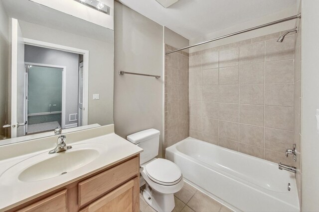 full bathroom featuring tile patterned flooring, tiled shower / bath combo, vanity, and toilet