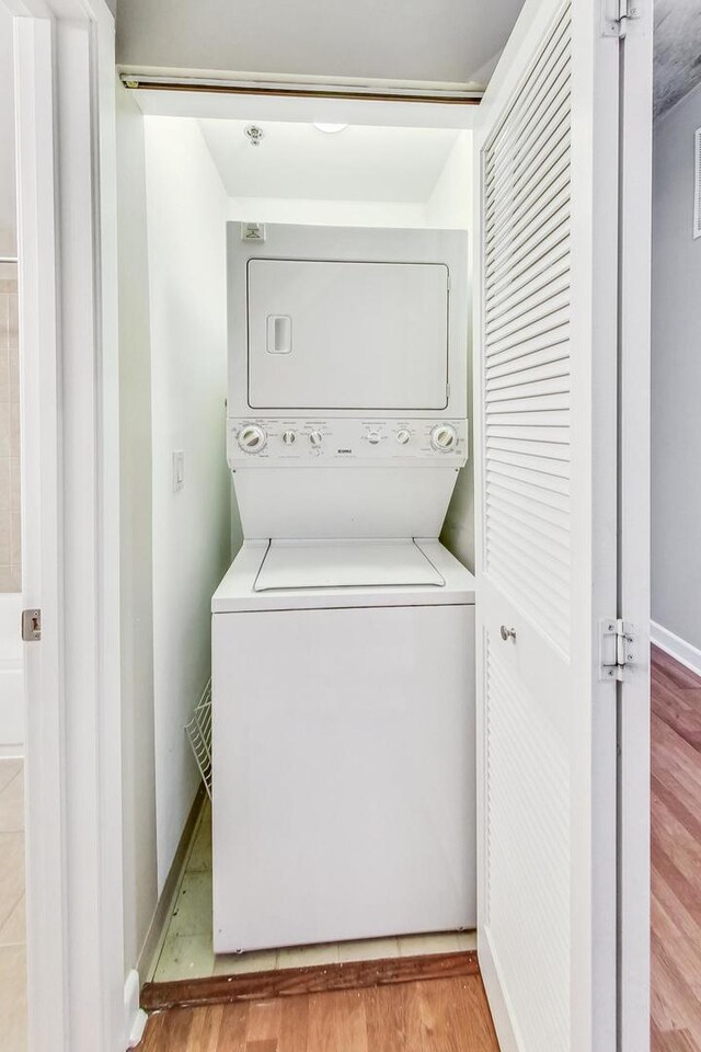 washroom with light wood-type flooring and stacked washer / drying machine