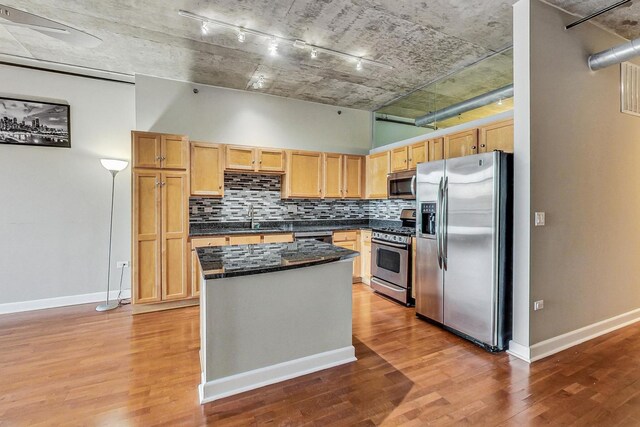 kitchen featuring dark stone counters, a center island, sink, light hardwood / wood-style flooring, and stainless steel appliances