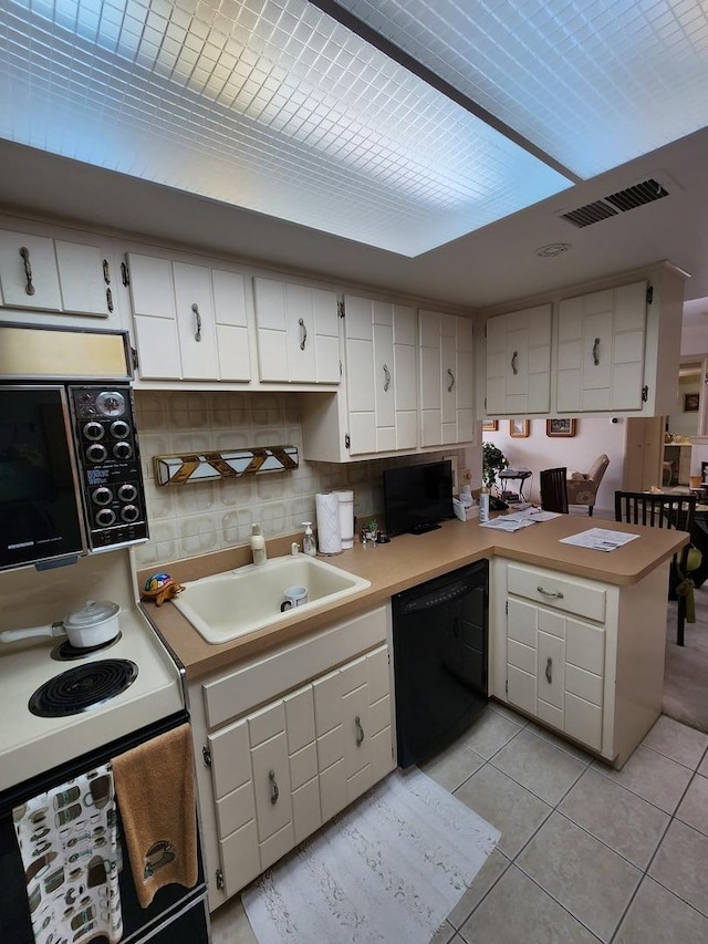 kitchen with light countertops, white cabinetry, a peninsula, light tile patterned floors, and black appliances