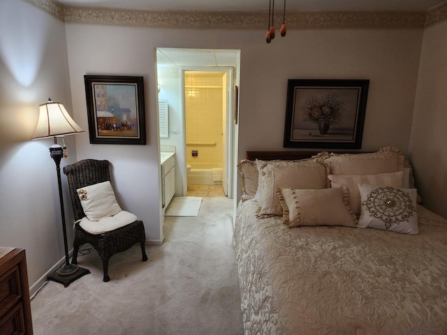 bedroom featuring baseboards, ensuite bath, and light colored carpet