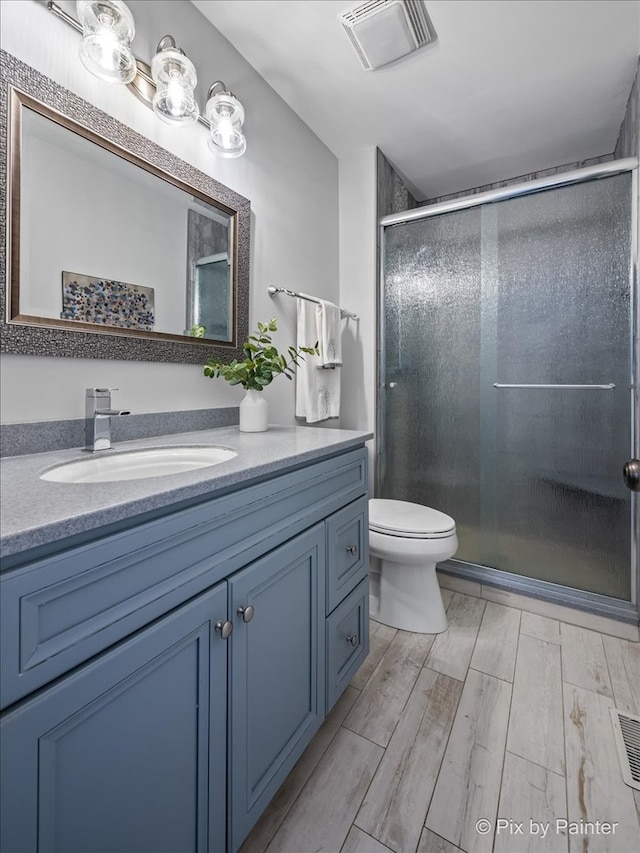 bathroom with vanity, toilet, and a shower with door