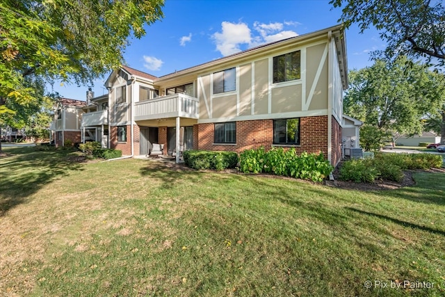 rear view of house featuring a balcony and a yard