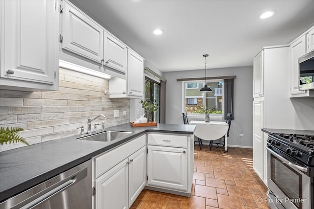 kitchen featuring kitchen peninsula, appliances with stainless steel finishes, sink, pendant lighting, and white cabinetry