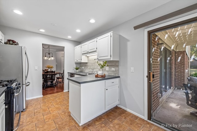 kitchen with white cabinets, a chandelier, stainless steel gas range oven, and tasteful backsplash