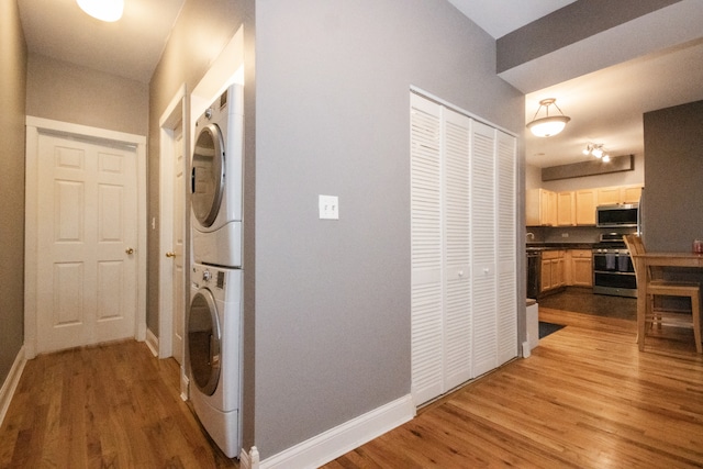 laundry room with stacked washer / drying machine and hardwood / wood-style flooring