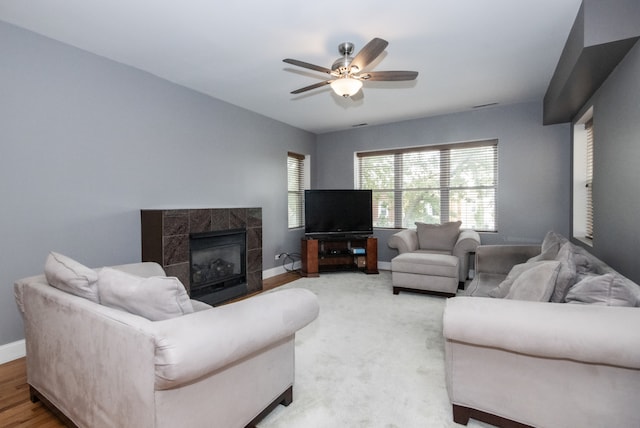 living room featuring ceiling fan, a tile fireplace, and hardwood / wood-style floors