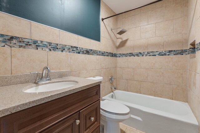 full bathroom featuring tile walls, vanity, tiled shower / bath combo, toilet, and tile patterned floors