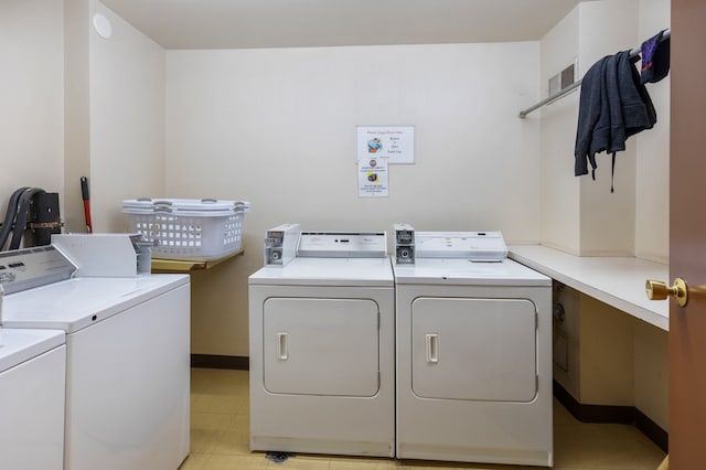 clothes washing area featuring light tile patterned floors and washer and dryer