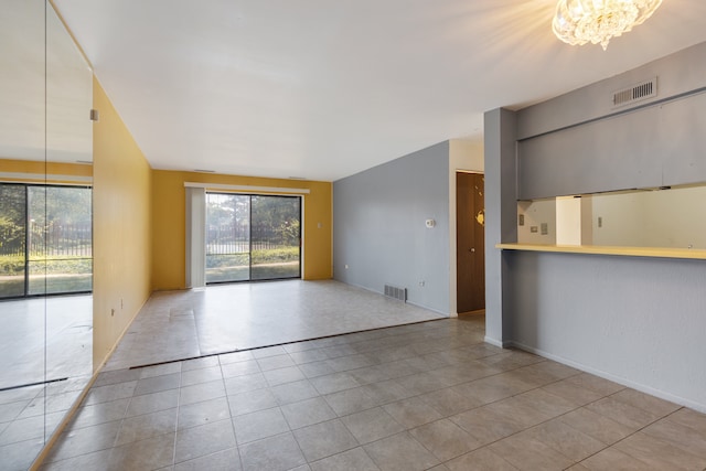 unfurnished room with a chandelier and light tile patterned floors