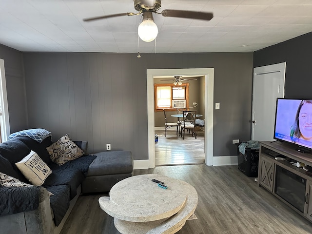 living room with ceiling fan, cooling unit, wooden walls, and hardwood / wood-style floors