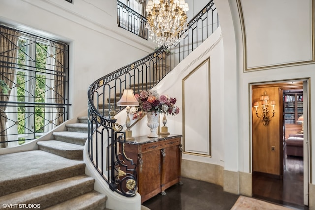 entrance foyer featuring hardwood / wood-style flooring, a towering ceiling, and a chandelier