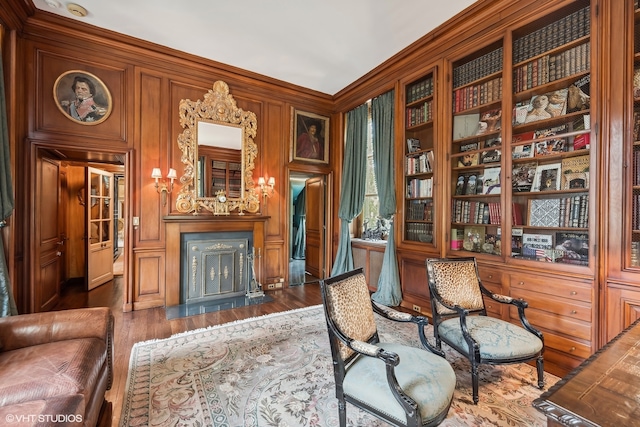 living area with ornamental molding, wood walls, dark hardwood / wood-style floors, and built in features