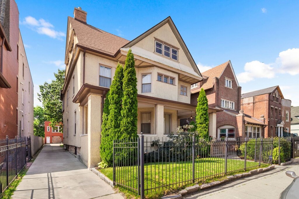 1031 E 45th St, Chicago, IL 60653 - view of front of house with a chimney, a fenced front yard, a front lawn, stucco siding, and roof with shingles
