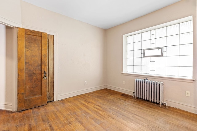 empty room with radiator heating unit and light hardwood / wood-style flooring