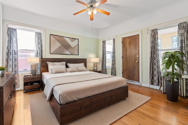 bedroom featuring ceiling fan, light hardwood / wood-style floors, and multiple windows