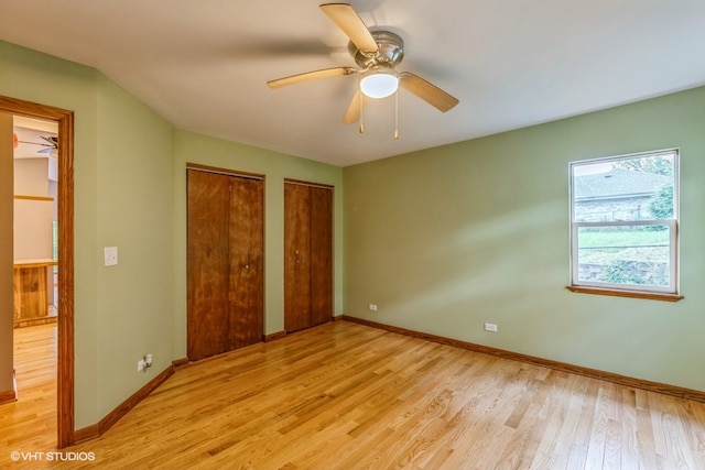 unfurnished bedroom with ceiling fan, multiple closets, and light hardwood / wood-style flooring