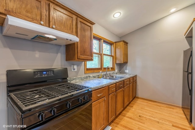 kitchen featuring fridge, lofted ceiling, light hardwood / wood-style flooring, gas stove, and sink