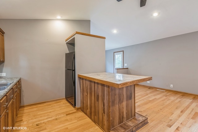 kitchen with fridge, light hardwood / wood-style floors, kitchen peninsula, and vaulted ceiling